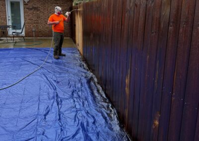Person staining wooden privacy fence