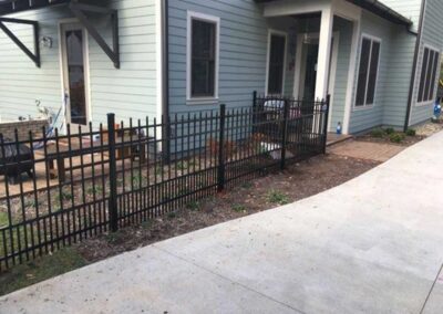 Black fence beside a house pathway.